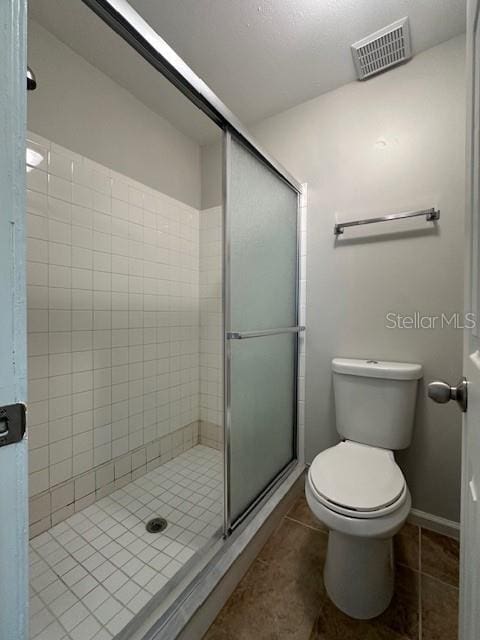 bathroom with toilet, a stall shower, tile patterned flooring, and visible vents