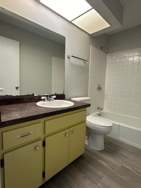 full bathroom featuring  shower combination, vanity, toilet, and wood finished floors