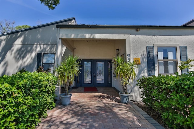 view of exterior entry featuring french doors and stucco siding