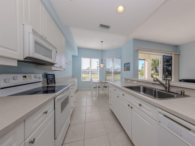 kitchen with white appliances, light countertops, a sink, and white cabinetry