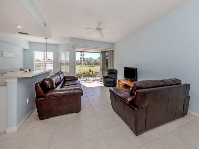 living room featuring a ceiling fan, a wealth of natural light, visible vents, and light tile patterned floors