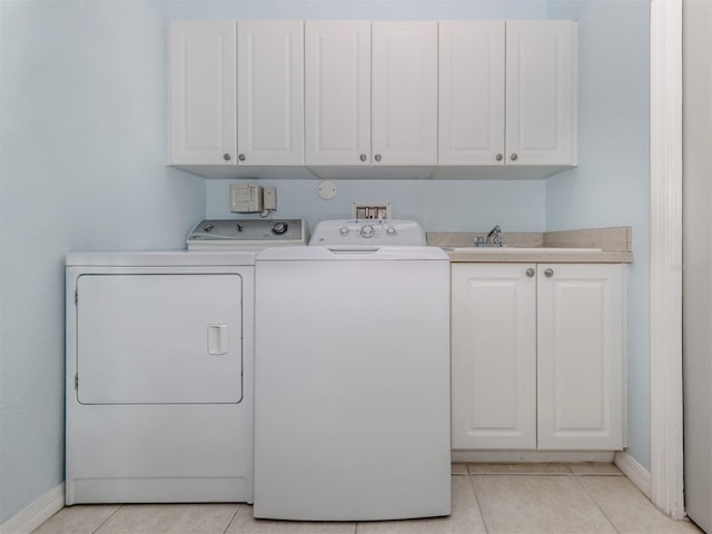 laundry room with light tile patterned flooring, washing machine and clothes dryer, cabinet space, and baseboards