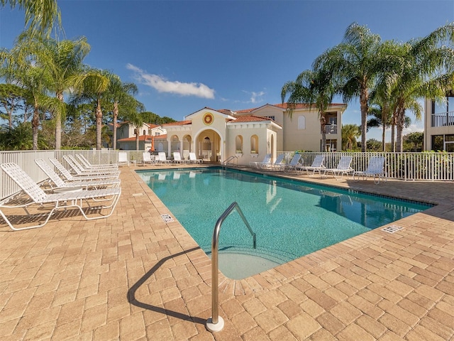 community pool with a patio area and fence