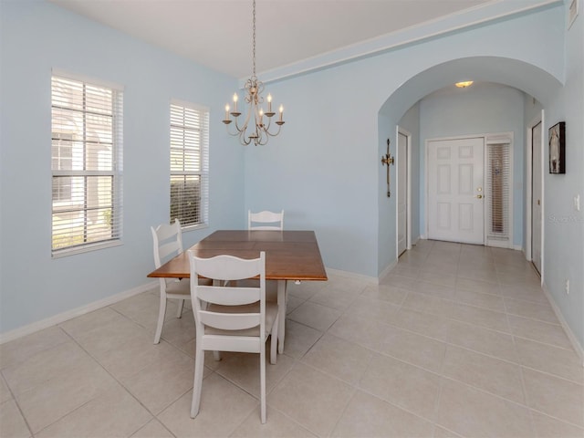 dining room with arched walkways, light tile patterned flooring, a notable chandelier, and baseboards