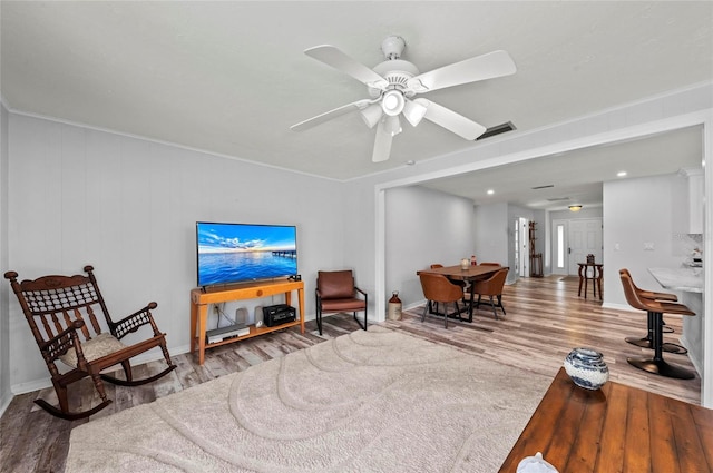 living room with ceiling fan, wood finished floors, visible vents, and baseboards