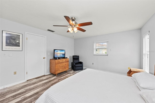 bedroom with ceiling fan, wood finished floors, and visible vents