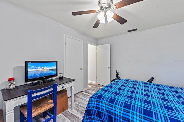 bedroom with a ceiling fan, visible vents, and wood finished floors