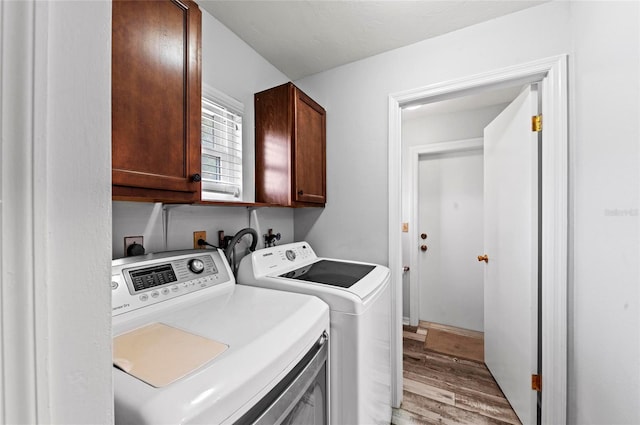 laundry room with cabinet space, light wood-style flooring, and washer and dryer