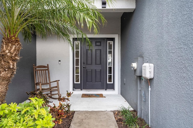 doorway to property featuring stucco siding