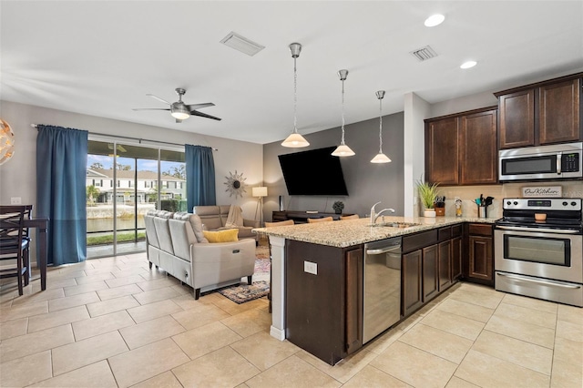 kitchen with appliances with stainless steel finishes, open floor plan, visible vents, and decorative light fixtures