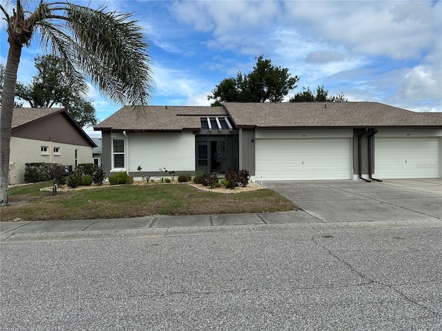 view of front of home featuring an attached garage, stucco siding, driveway, and a front yard