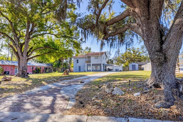 view of front of property featuring an outbuilding, a front lawn, decorative driveway, and a storage unit