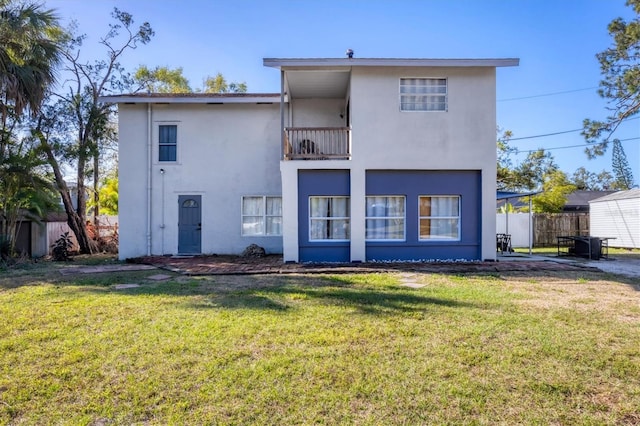 back of house with a yard, stucco siding, a patio area, fence, and a balcony