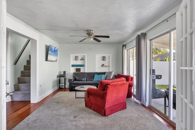 living room with a textured ceiling, wood finished floors, baseboards, stairs, and built in features