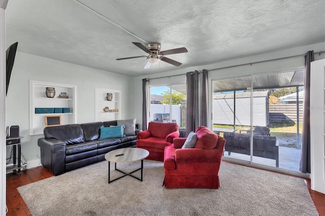 living area with a ceiling fan, a textured ceiling, built in features, and wood finished floors