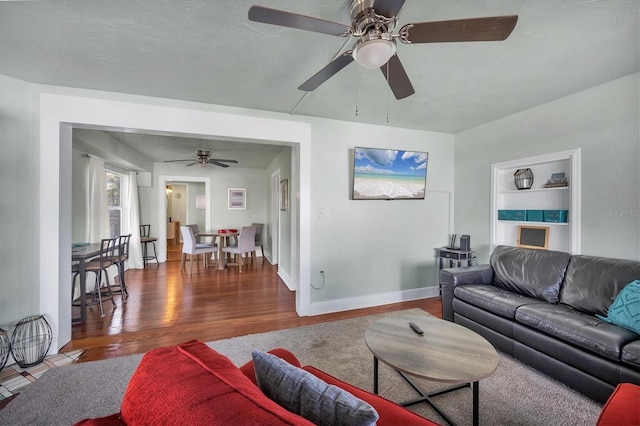 living area with baseboards and wood finished floors