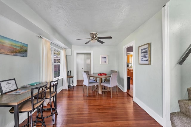 dining space featuring stairway, baseboards, dark wood finished floors, and a ceiling fan