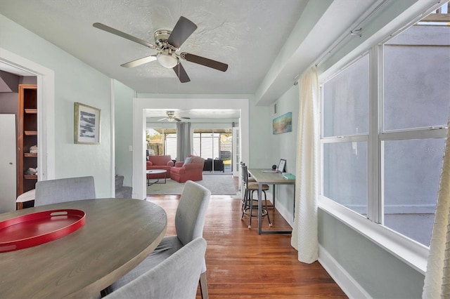 dining room with a textured ceiling, baseboards, and wood finished floors