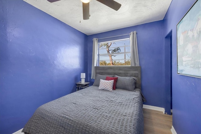 bedroom with a textured ceiling, wood finished floors, a ceiling fan, and baseboards