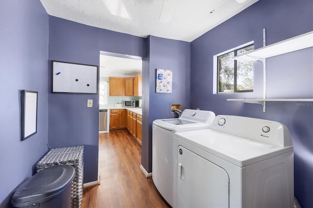 clothes washing area with laundry area, wood finished floors, washer and dryer, and a healthy amount of sunlight