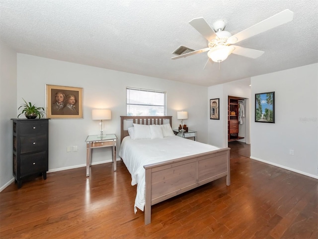 bedroom featuring ceiling fan, a textured ceiling, baseboards, and dark wood-type flooring