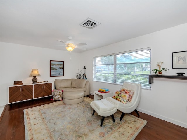 sitting room with a ceiling fan, visible vents, dark wood finished floors, and baseboards