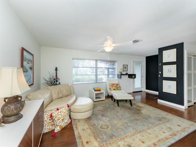 living area with a ceiling fan, visible vents, dark wood finished floors, and baseboards