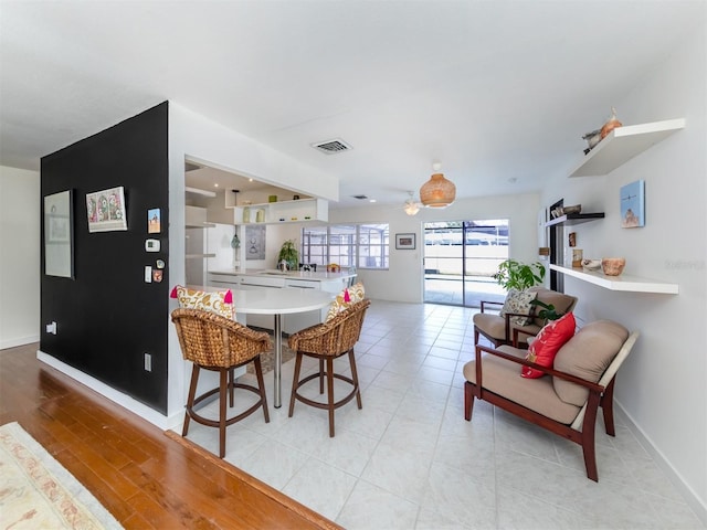 dining area with light wood-type flooring, visible vents, and baseboards