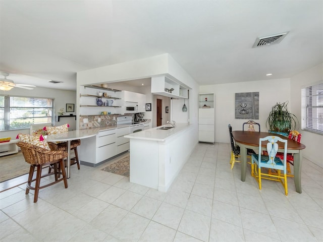 kitchen with open shelves, light countertops, white cabinets, a sink, and a peninsula