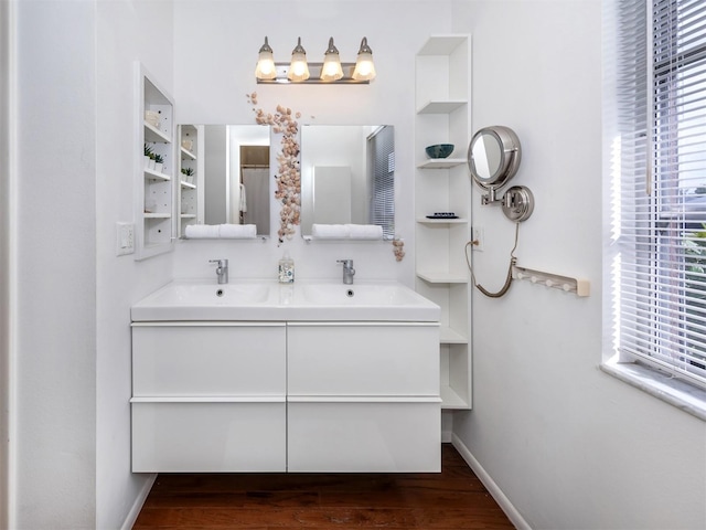 full bathroom featuring double vanity, a sink, built in features, and baseboards