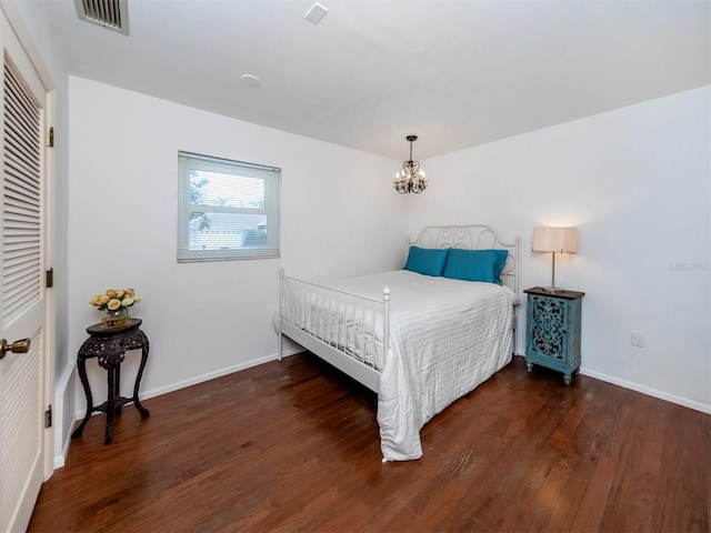 bedroom featuring dark wood-style floors, visible vents, baseboards, and an inviting chandelier