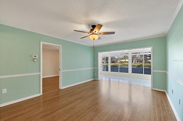 empty room with baseboards, ceiling fan, ornamental molding, wood finished floors, and a textured ceiling