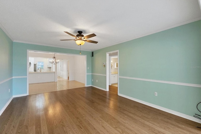 unfurnished room with baseboards, ornamental molding, wood finished floors, a sink, and ceiling fan with notable chandelier