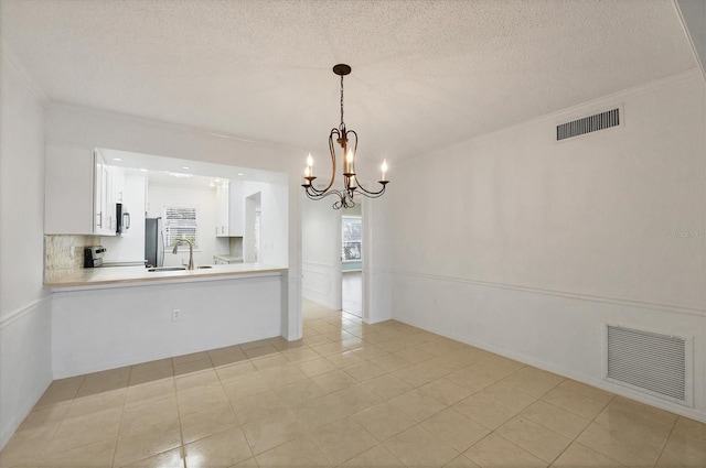 interior space with a textured ceiling, a sink, visible vents, and a notable chandelier