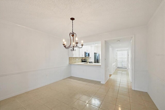 unfurnished dining area featuring a textured ceiling, ornamental molding, light tile patterned floors, and a notable chandelier