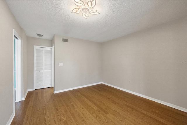 empty room featuring baseboards, a textured ceiling, visible vents, and dark wood-style flooring