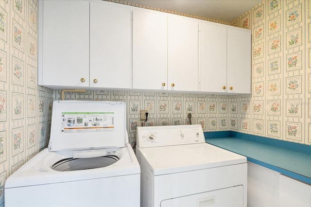 laundry area featuring wallpapered walls, cabinet space, and independent washer and dryer