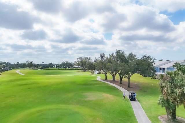 view of property's community featuring view of golf course and a lawn