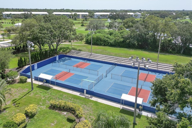 view of tennis court with a lawn and fence