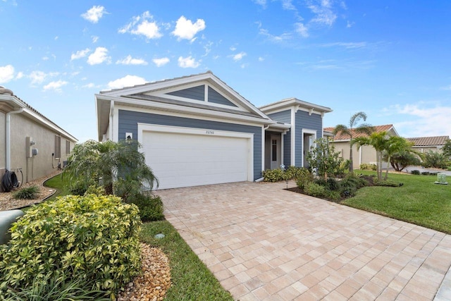 view of front of home featuring an attached garage, decorative driveway, and a front yard