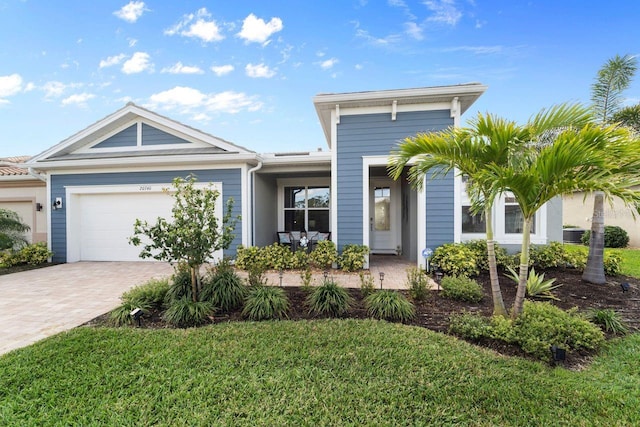 view of front of home with a front lawn, decorative driveway, and an attached garage