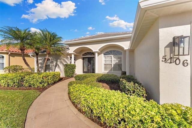 property entrance featuring a tiled roof and stucco siding