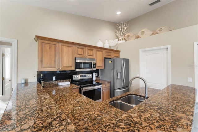 kitchen featuring visible vents, appliances with stainless steel finishes, dark stone countertops, a peninsula, and a sink