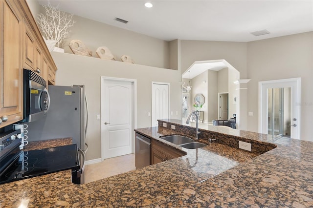 kitchen with light tile patterned floors, a sink, visible vents, appliances with stainless steel finishes, and dark stone counters