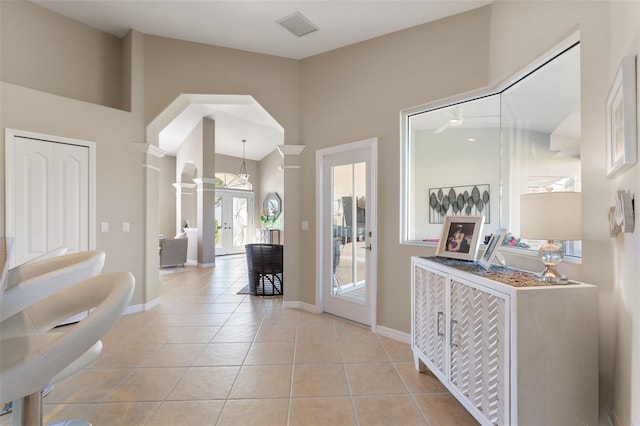 foyer entrance featuring visible vents, baseboards, french doors, ornate columns, and light tile patterned flooring