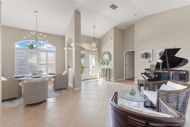 living room featuring visible vents, an inviting chandelier, light tile patterned flooring, high vaulted ceiling, and ornate columns