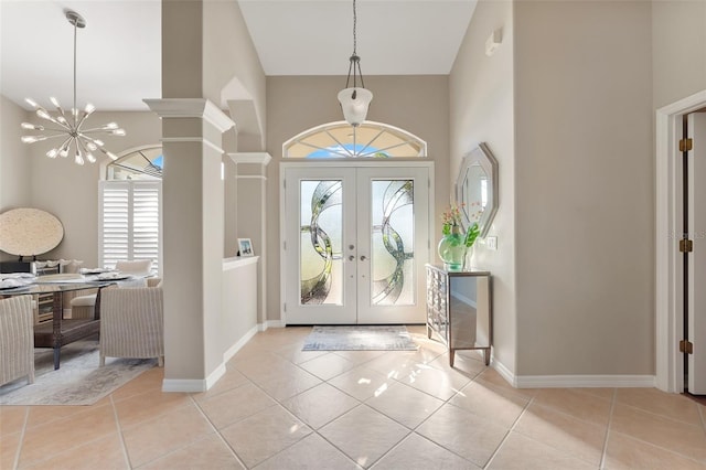 entrance foyer with a healthy amount of sunlight, a towering ceiling, french doors, and light tile patterned flooring