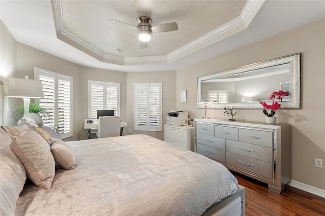 bedroom featuring a tray ceiling, dark wood-style flooring, ornamental molding, ceiling fan, and baseboards