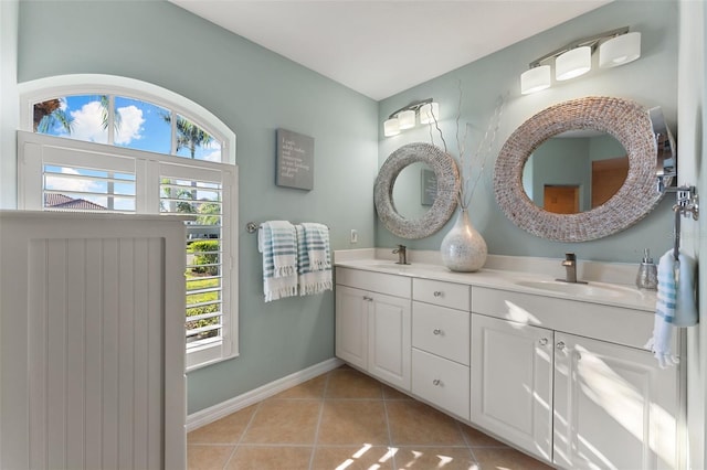 full bath with double vanity, tile patterned flooring, a sink, and baseboards