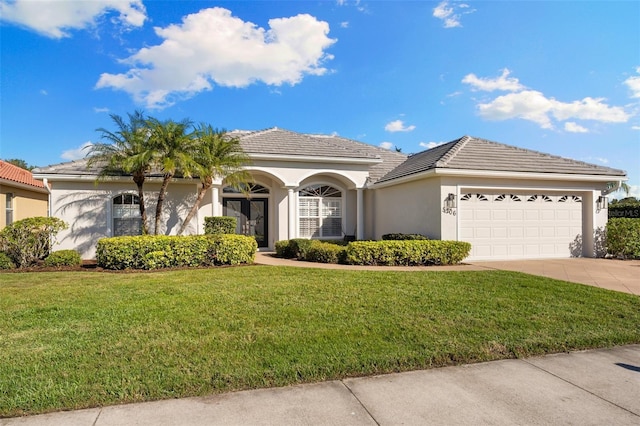 ranch-style home featuring a garage, a tile roof, driveway, stucco siding, and a front lawn